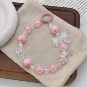 Sweet pink beaded phone charm with iridescent bow and donut ring, keychain accessory.