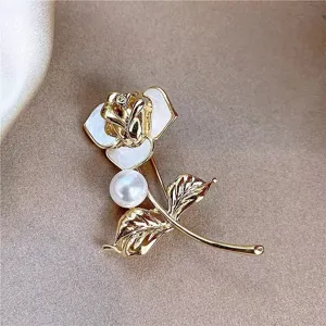 Exquisite gold rose brooch with white petals and elegant pearl detail on textured fabric