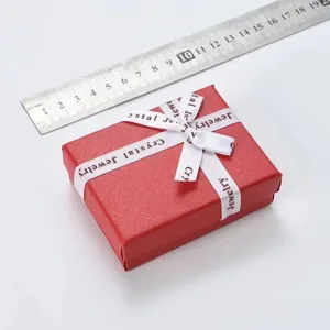 Rode sieraden geschenkdoos met wit lint en liniaal voor een duidelijke maatreferentie