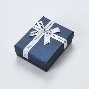 Detailopname van een marineblauwe sieradendoos met wit Crystal Jewelry lint gestrikt