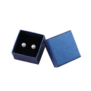 Detailweergave van elegante witte pareloorbellen in een blauw getextureerd doosje
