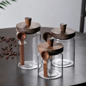 Glass storage jar detail with wooden lid and matching spoon for coffee beans and tea leaves.
