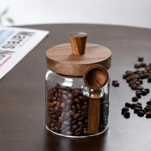 Glass coffee bean storage jar with wooden lid and spoon for kitchen pantry organization.