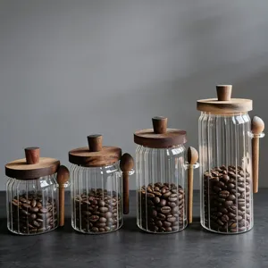 Set van vier doorzichtige geribbelde glazen voorraadpotten met houten deksels en lepels.