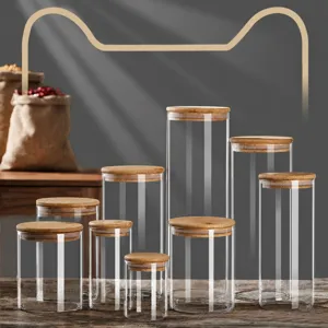 Glass storage jars with wooden lids, set of multiple sizes for kitchen pantry organization.