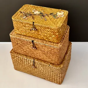 Detailed view of three stacked handmade woven straw storage boxes with elegant floral embroidery