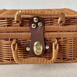 Close-up detail of a hand-woven rattan gift box with golden metal latch and leather strap