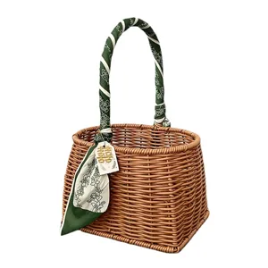 Geweven rattan geschenkmand met groene zijden sjaal handvatwikkel en decoratief label voor bruiloften.