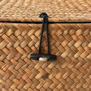 Detailed view of the elastic cord and wooden toggle closure on a woven rattan gift box