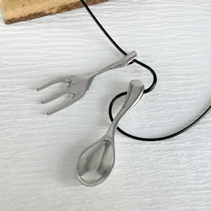 Macro detail view of creative polished silver fork and spoon charms on a black cord necklace
