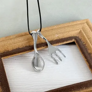 Macro view of unique spoon and fork pendants with polished silver metallic finish