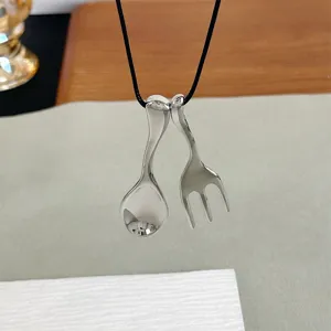 Detail view of a stylish creative silver spoon and fork pendant necklace for women.