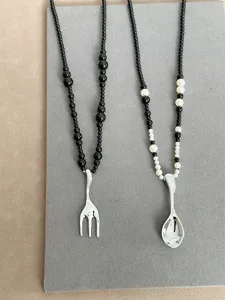 Detailed view of creative silver-toned fork and spoon pendant necklaces with beads
