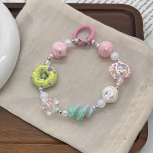 Close-up detail of a colorful beaded phone charm featuring a hand-painted donut bead design