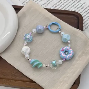 Detail view of colorful dopamine style phone charm with hand-painted beads and donut.