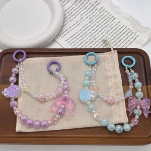 Close-up detail of handmade beaded phone charms with butterfly and donut pendants in pastel colors
