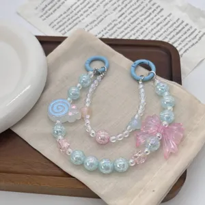 Detailed shot of pastel beaded phone charm featuring pink bow and blue lollipop pendant