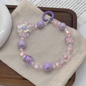 Detailed view of a purple and pink handmade beaded phone charm featuring floral and heart accents.