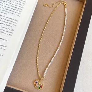 Collier élégant asymétrique en perles et or avec pendentif cheval de Troie coloré.