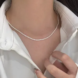 Macro view of a delicate sparkling stardust silver chain necklace worn on the neck.