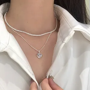 Close-up of double-layered silver necklace with sparkling texture and crystal pendant