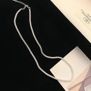 Detail macro view of sparkling silver wave chain necklace shown on black velvet tray.