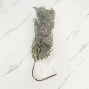 Künstlicher Kiefernzweig mit Kiefernzapfen in einer klaren Schutzverpackung aus Plastik