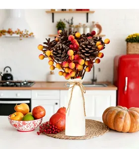 A detailed view of artificial pinecones and colorful berries arranged in a white vase.