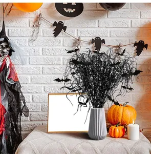 Detailansicht Halloween Glitzer Fledermaus Zweige in grauer Vase mit herbstlichen Kuerbissen.