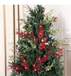 Red and green glittery artificial branches decorating a green Christmas tree detail