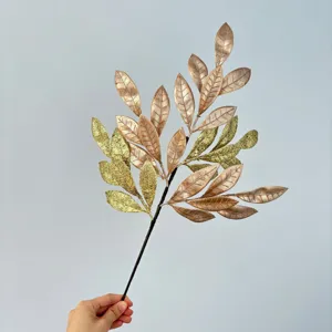 Detailed close-up view of artificial Christmas glitter gold leaf branch for holiday party decor.