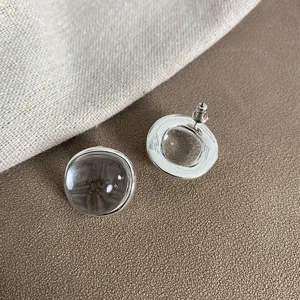 Primo piano di orecchini tondi in argento con pietre di cristallo trasparente.