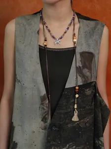 Detail van vintage zebra kralenketting op model met een bedrukte gilet en kwastje.