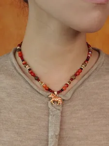 Detailopname van een retro zebra-kralenketting met rode agaatkralen en goud hanger