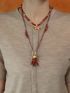 Detailopname van de gelaagde retro zebra kralenketting en kwastjeshanger op het model.