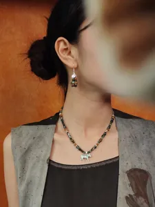 Gedetailleerd aanzicht van een retro kralenketting met een zilveren zebra-hanger