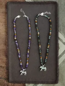 Gedetailleerd overzicht van twee vintage kralenkettingen met zilveren zebrahangers op een blad.