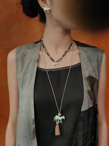 Vintage kralenketting met zebra-bedel en kwastje hanger gedragen door een model nu