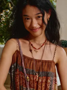 Close-up van een vintage kralenketting met een goudkleurige zebra hanger op een model
