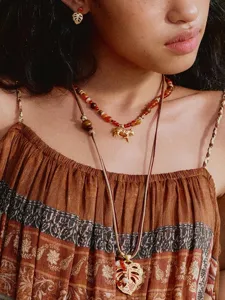 Gedetailleerde weergave van vintage kralenketting met gouden zebrahanger en blad.