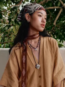 Detail van een retro zebra kralenketting gedragen door een model in een resortomgeving.
