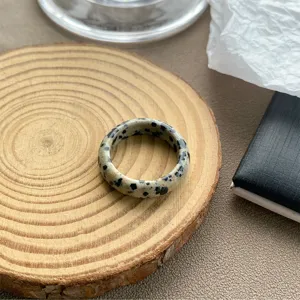 Makrodetail eines Retro-Harzrings mit Dalmatinerstein-Muster auf einem Holzständer