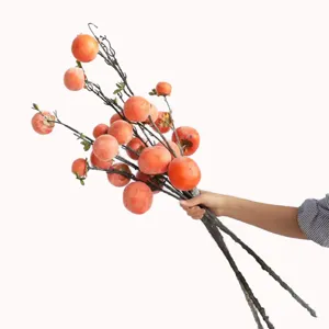 Detail view of realistic frosted artificial persimmon branches held to show scale.