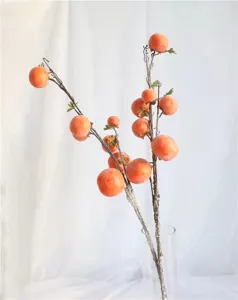 Realistic frosted artificial persimmon branches in a clear glass vase for home decor.