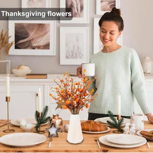Vibrant artificial pumpkin and berry stems set in a vase on a Thanksgiving table