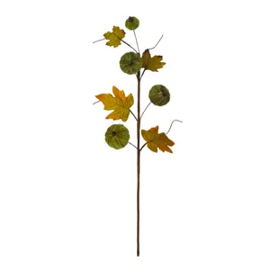 Detailed view of artificial branch with green velvet pumpkins and autumn maple leaves.