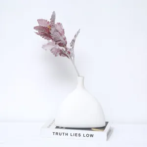 Elegante foglia di cineraria finta floccata rosa antico in un vaso bianco dallo stile minimal