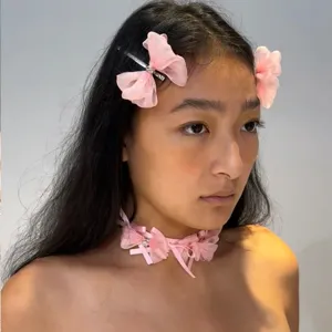 Détail d'un ras de cou rose avec nœud en ruban et zircons porté par un mannequin