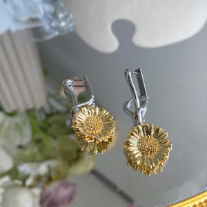 Detailopname van elegante zilveren en gouden madeliefje oorbellen op een spiegeloppervlak