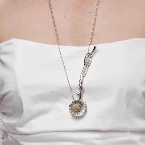 Detailopname van een zilveren madeliefjesketting met gouden hartje en artistieke steel